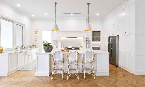 This light, airy and timeless shaker kitchen is a dream, with brushed brass handles, Stone Ambassador benchtops in a matt finish, plentiful storage and sturdy stools from Provincial Home Living.