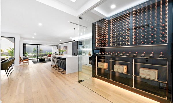 With frameless glazing, black shelving and a smoked mirror, the wine room is a stunning feature in the centre of the home. 